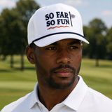 A man wearing a white imperial rope cap with 'SO FAR SO FUN' printed on the front, photographed outdoors on a golf course.